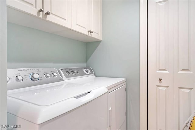 washroom with cabinets and washing machine and clothes dryer