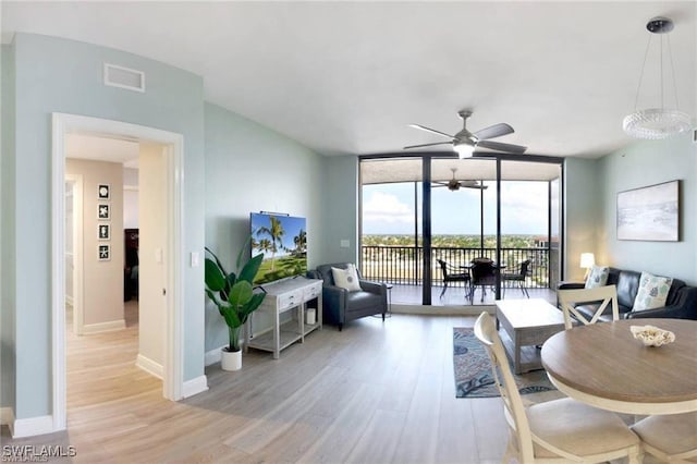 living room featuring ceiling fan, a wall of windows, and light wood-type flooring