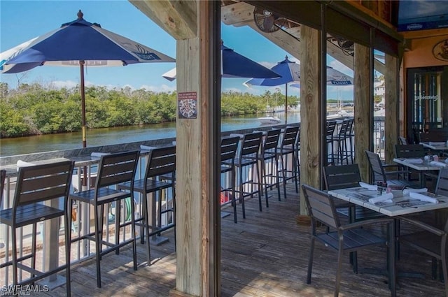 wooden terrace with a water view and an outdoor bar