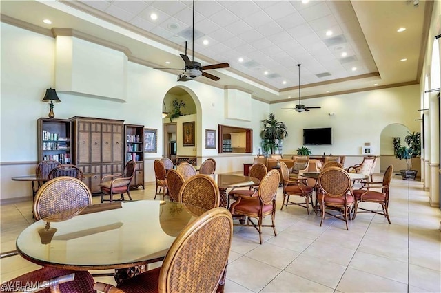 tiled dining area with a high ceiling, a raised ceiling, and ceiling fan