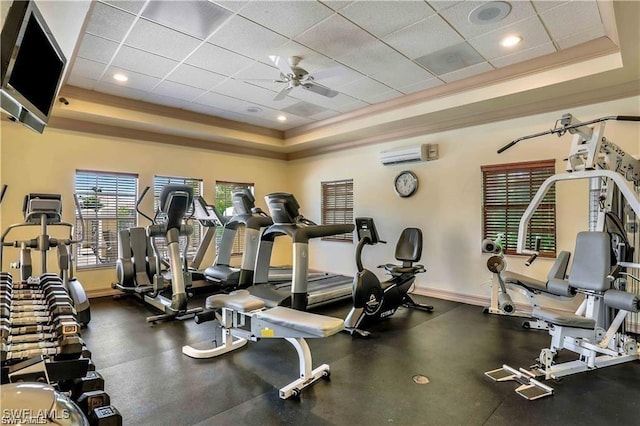 gym featuring ceiling fan, a wall unit AC, crown molding, a tray ceiling, and a paneled ceiling