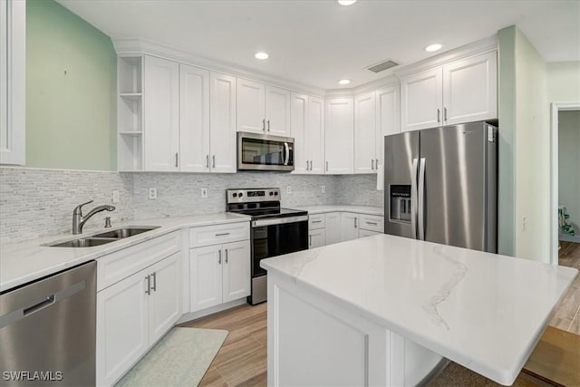 kitchen featuring light stone countertops, stainless steel appliances, sink, light hardwood / wood-style flooring, and white cabinetry