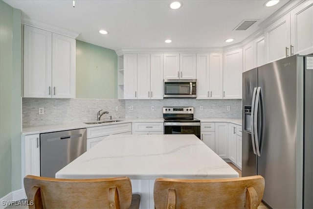 kitchen featuring appliances with stainless steel finishes, white cabinetry, a kitchen island, and sink