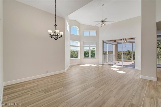 unfurnished living room featuring high vaulted ceiling, ceiling fan with notable chandelier, and light wood-type flooring