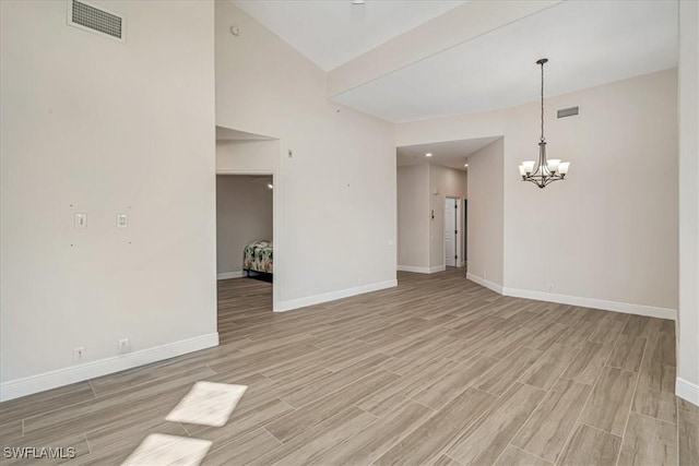 empty room featuring light wood-type flooring and an inviting chandelier