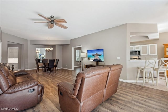 living room featuring ceiling fan with notable chandelier and hardwood / wood-style floors