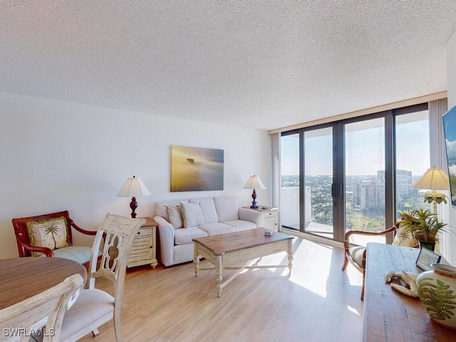 living room with expansive windows, light wood-type flooring, and a textured ceiling