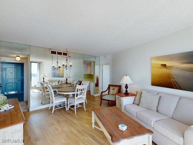 living room with a textured ceiling, light hardwood / wood-style flooring, and a notable chandelier