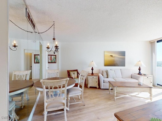 dining space featuring an inviting chandelier, a textured ceiling, and hardwood / wood-style flooring