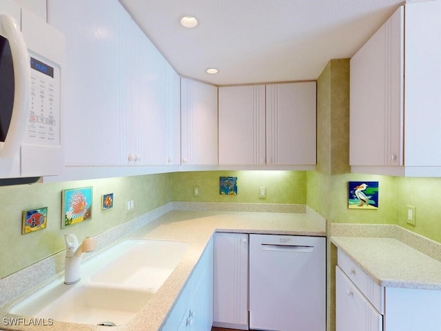 kitchen featuring sink, white cabinets, and white appliances