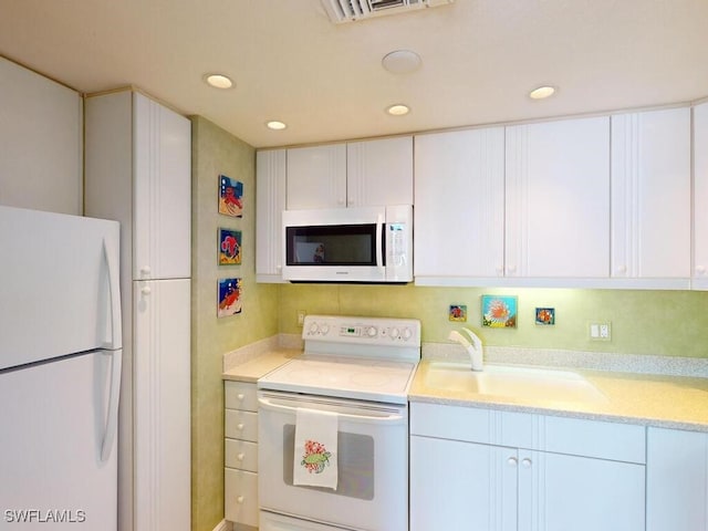 kitchen with sink, white cabinets, and white appliances