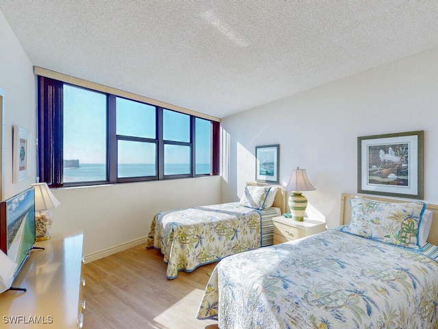 bedroom with a textured ceiling and light hardwood / wood-style flooring