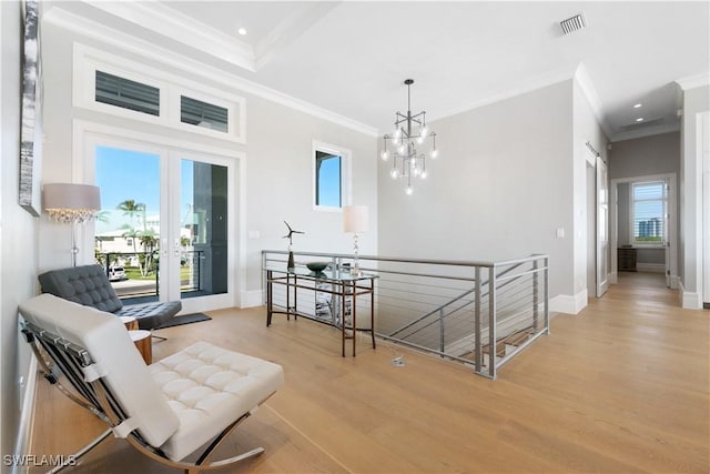 living area featuring light wood-type flooring, ornamental molding, and an inviting chandelier