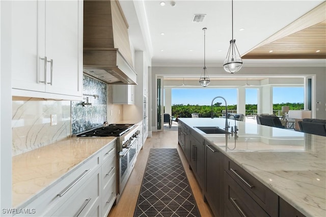 kitchen featuring light stone counters, double oven range, white cabinetry, and sink