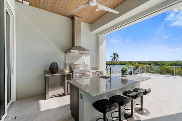 view of patio with a grill, a water view, ceiling fan, and a wet bar