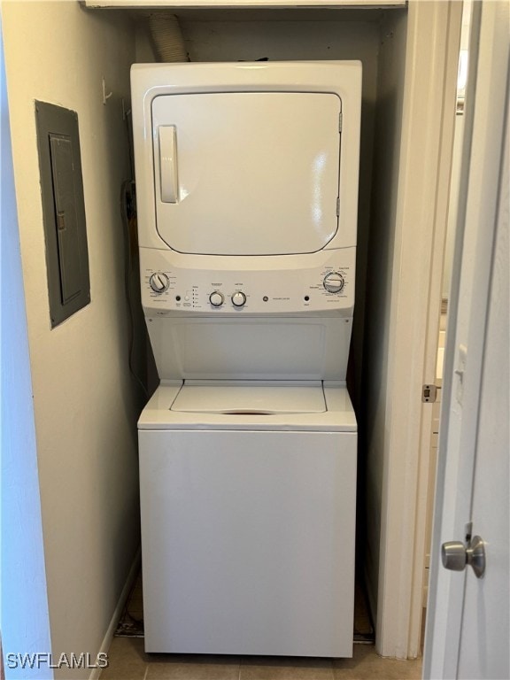 washroom featuring electric panel, stacked washer and dryer, and light tile patterned floors