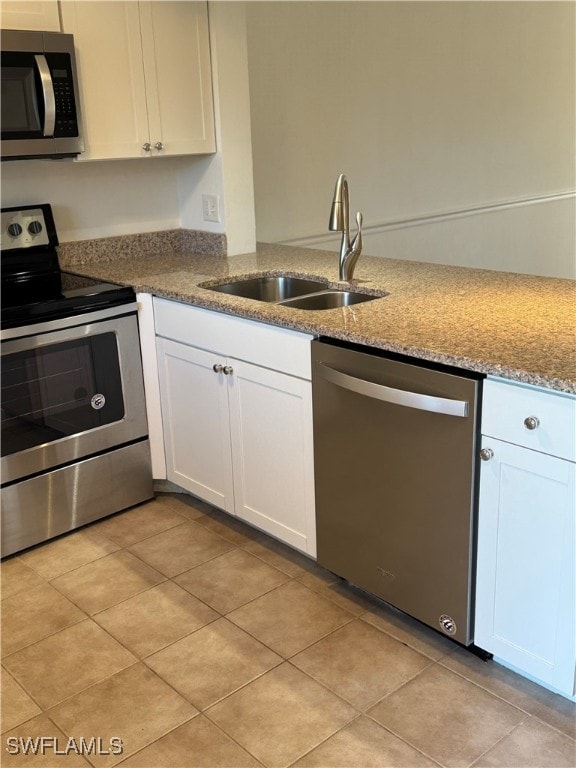 kitchen featuring white cabinets, stainless steel appliances, light stone counters, and sink