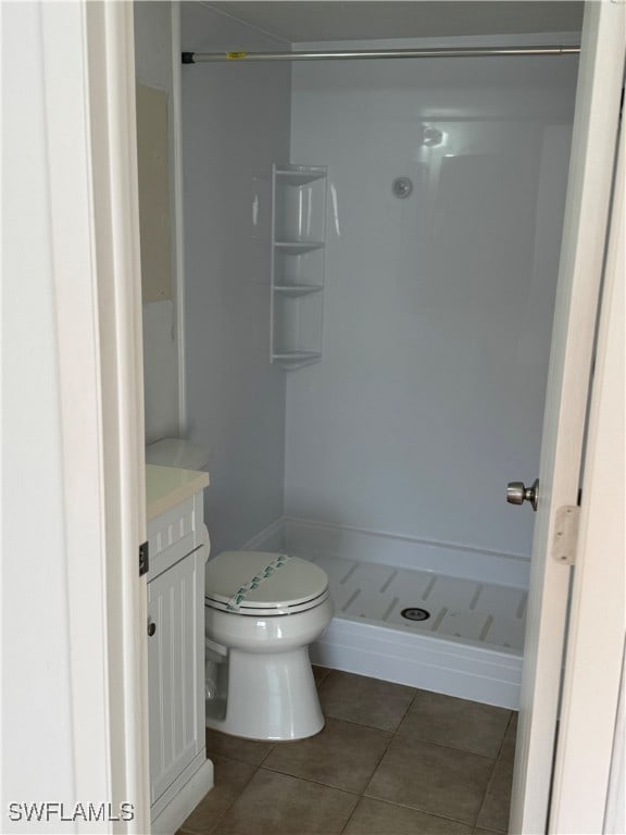 bathroom featuring tile patterned floors, a shower, vanity, and toilet