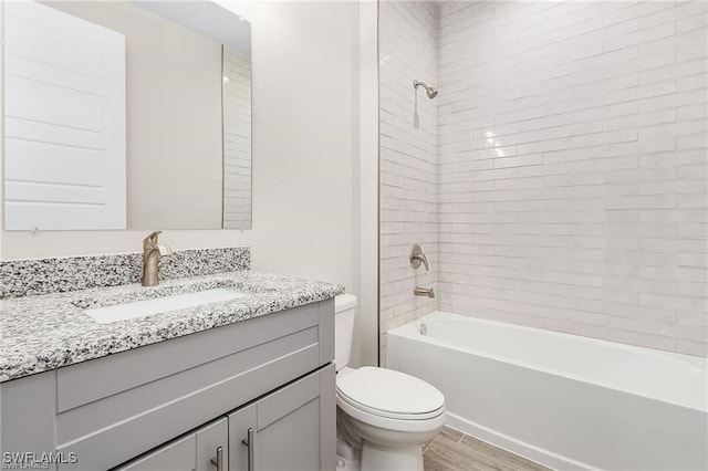 full bathroom with vanity, tiled shower / bath combo, hardwood / wood-style flooring, and toilet