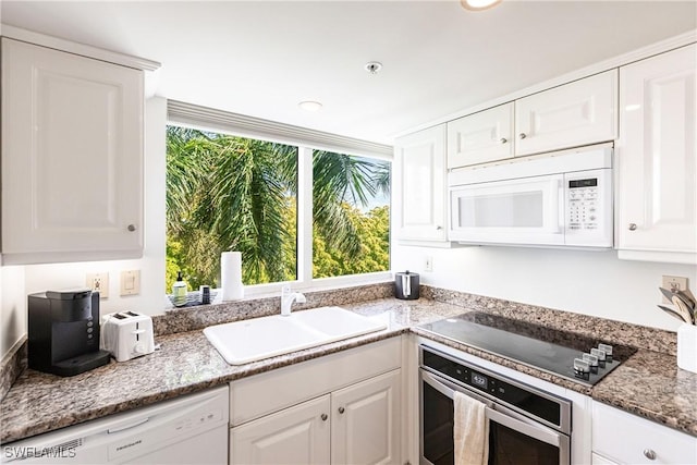 kitchen with stone counters, stainless steel appliances, white cabinetry, and sink