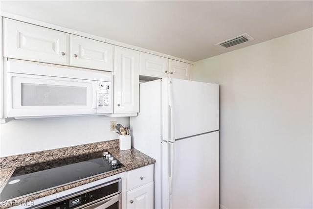 kitchen featuring white cabinets, stainless steel appliances, and dark stone countertops