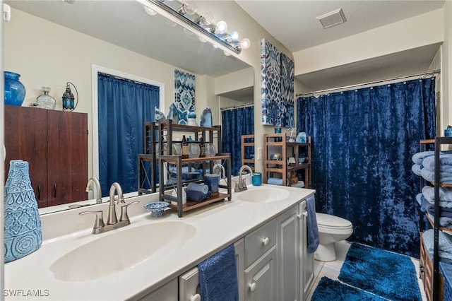 bathroom with tile patterned floors, vanity, toilet, and a textured ceiling