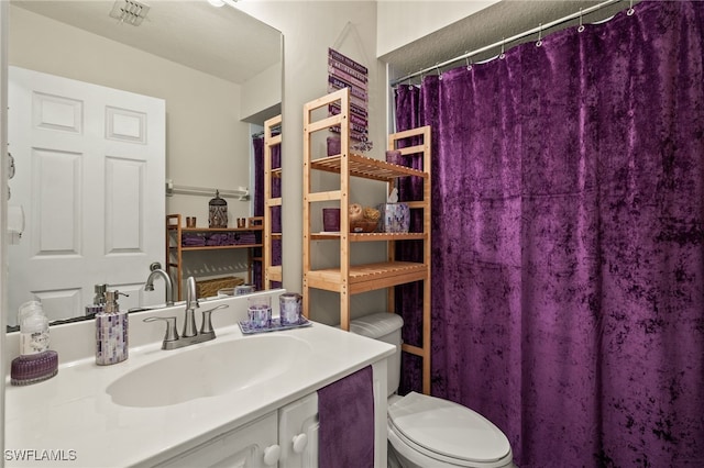 bathroom featuring walk in shower, vanity, and toilet