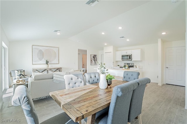 dining space with light hardwood / wood-style floors and vaulted ceiling