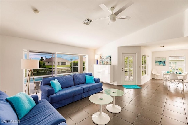 living room featuring ceiling fan, dark tile patterned floors, and lofted ceiling