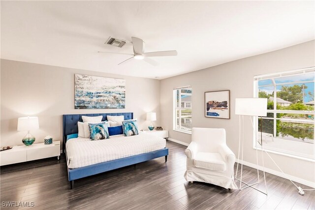 bedroom featuring dark hardwood / wood-style flooring, multiple windows, and ceiling fan