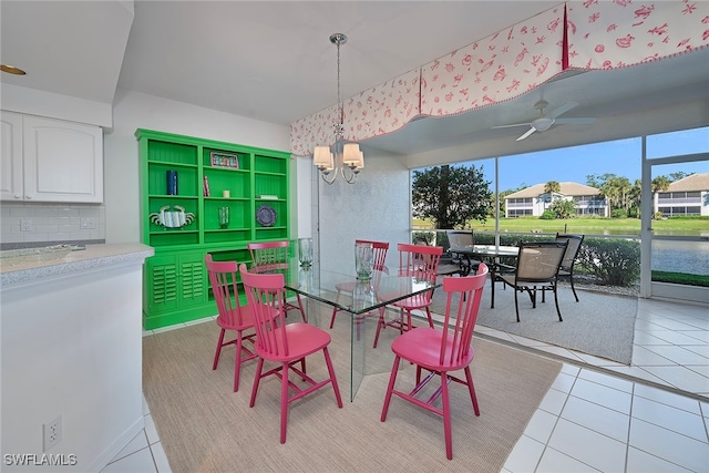 dining area with light tile patterned floors, ceiling fan with notable chandelier, and a water view