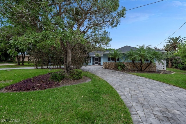 single story home with decorative driveway and a front yard
