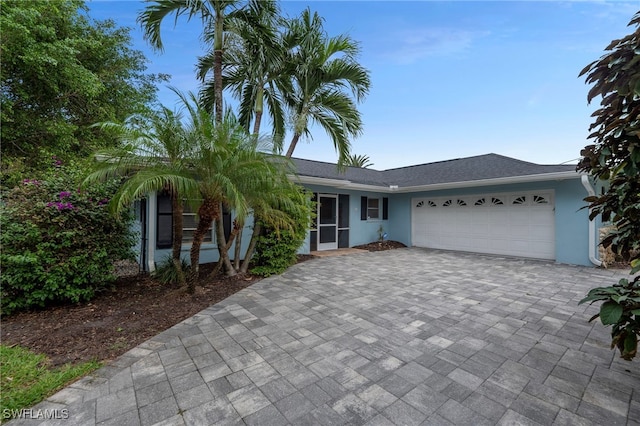 view of front facade featuring decorative driveway, an attached garage, and stucco siding