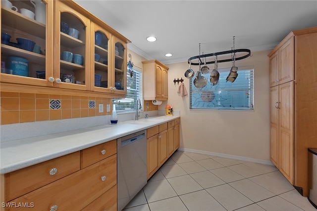 kitchen with glass insert cabinets, light countertops, a sink, and stainless steel dishwasher