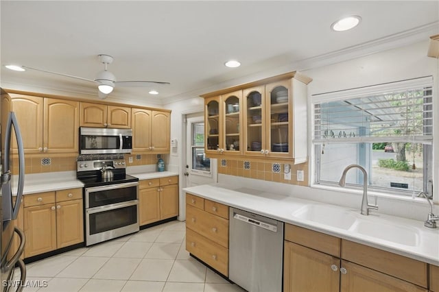 kitchen featuring decorative backsplash, crown molding, appliances with stainless steel finishes, a sink, and glass insert cabinets
