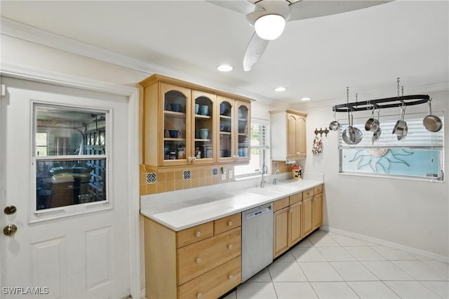 kitchen featuring a sink, dishwasher, baseboards, ornamental molding, and glass insert cabinets