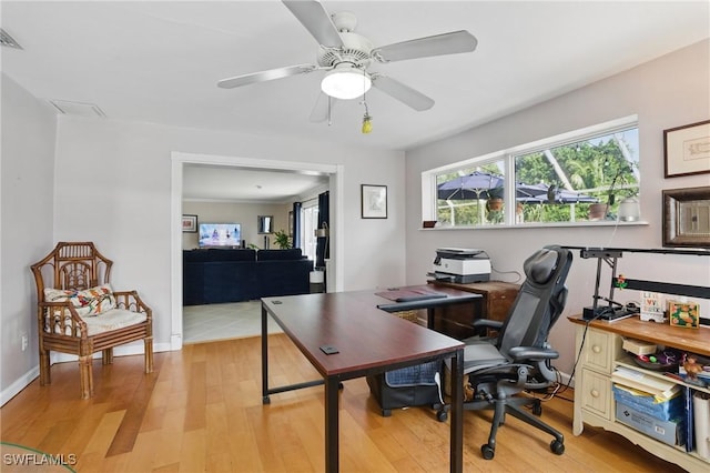 home office featuring light wood-style floors, a ceiling fan, and baseboards