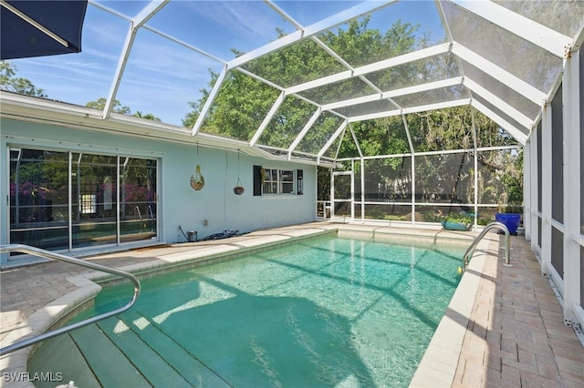 outdoor pool featuring glass enclosure and a patio