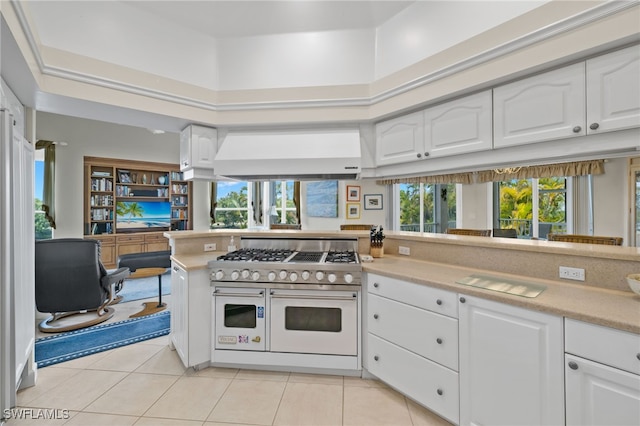 kitchen featuring ventilation hood, a healthy amount of sunlight, double oven range, and white cabinets