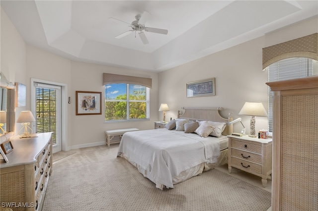 carpeted bedroom featuring ceiling fan and a tray ceiling