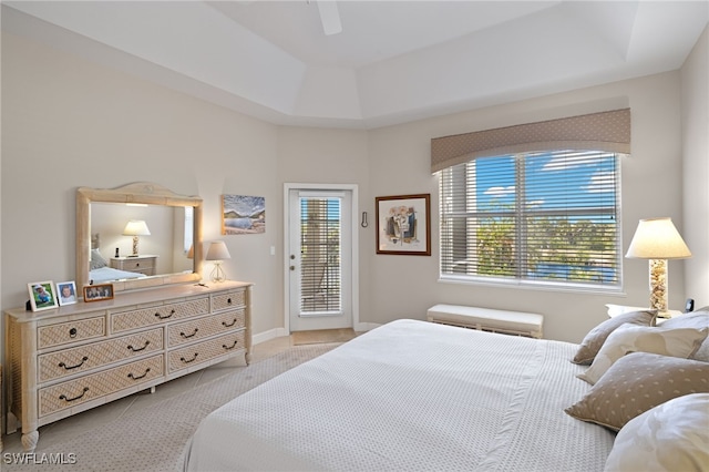 bedroom with access to outside, multiple windows, ceiling fan, and a tray ceiling