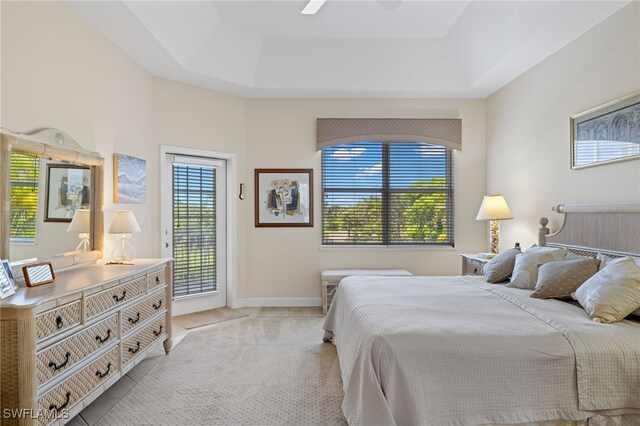 carpeted bedroom with access to outside, multiple windows, ceiling fan, and a raised ceiling