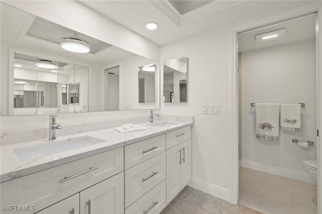 bathroom featuring a raised ceiling, vanity, ornamental molding, and toilet