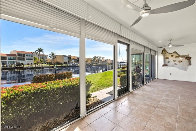 unfurnished sunroom featuring a water view and ceiling fan