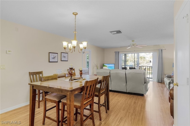 dining area with ceiling fan with notable chandelier and light hardwood / wood-style flooring