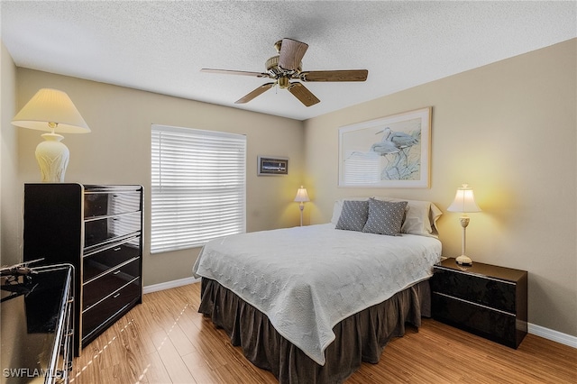 bedroom featuring ceiling fan, a textured ceiling, and light wood-type flooring