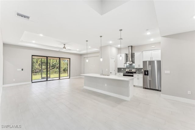 kitchen with stainless steel appliances, ceiling fan, decorative light fixtures, white cabinetry, and an island with sink