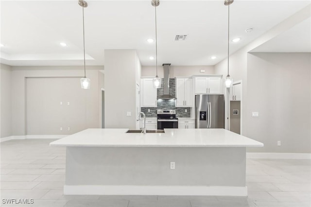 kitchen with appliances with stainless steel finishes, wall chimney exhaust hood, sink, decorative light fixtures, and white cabinetry