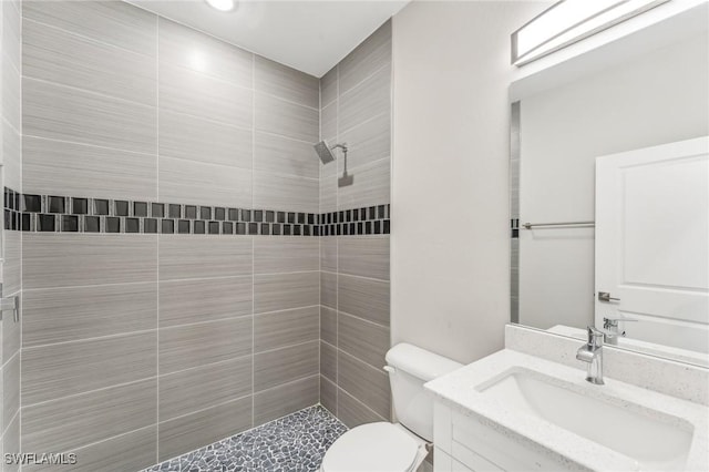 bathroom with vanity, toilet, and tiled shower