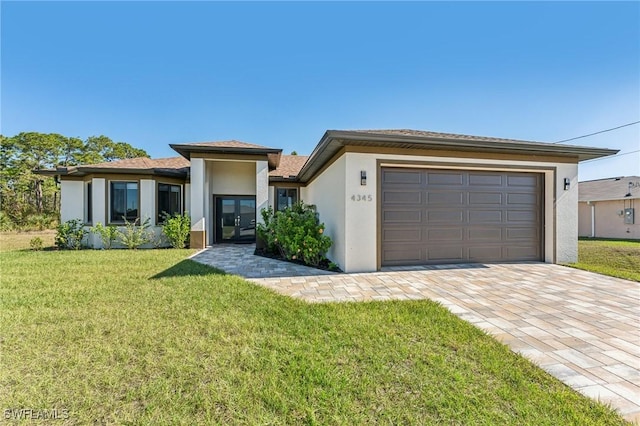 prairie-style home with french doors, a front yard, and a garage